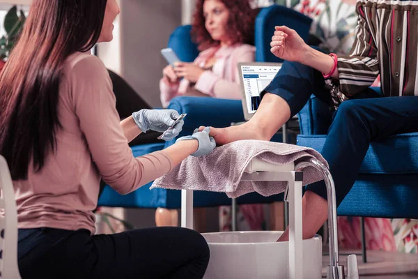 Pleasant nice woman holding her clients foot