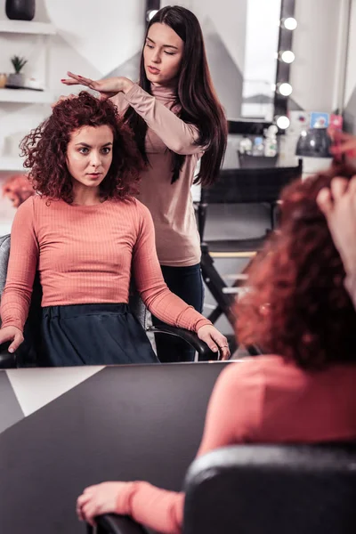 Nice professional hairdresser pointing at the hair — Stock Photo, Image