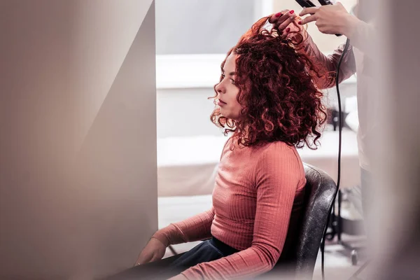 Nice red haired woman having her hair straightened — Stock Photo, Image