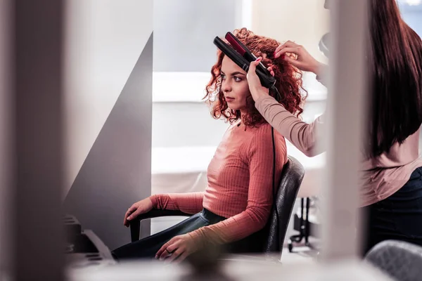 Cabeleireiro profissional qualificado usando um alisador de cabelo — Fotografia de Stock