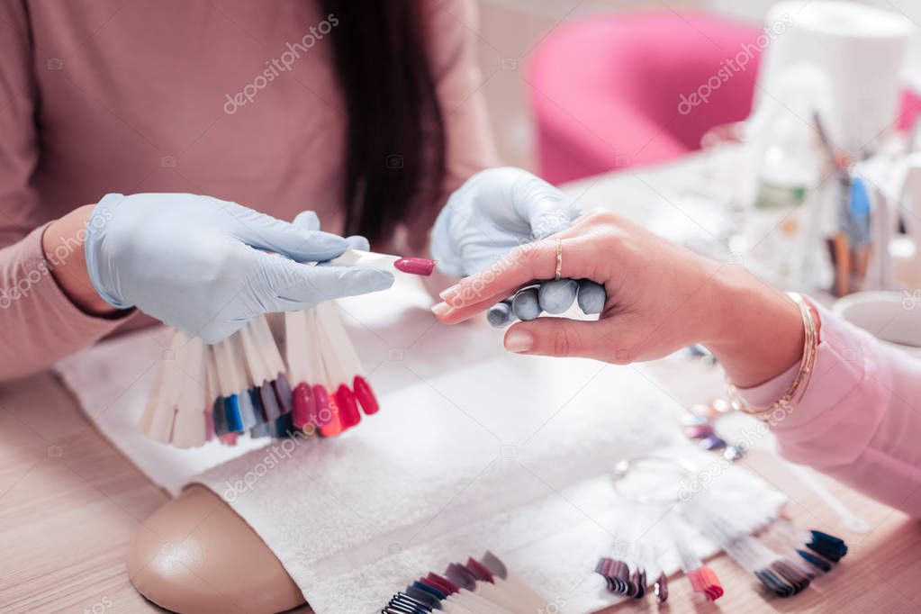 Professional manicure master holding an artificial nail
