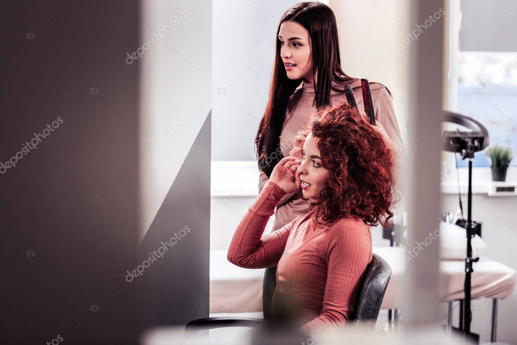 Pleasant young woman speaking to her hair stylist