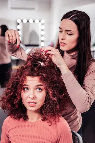 Trevlig allvarlig kvinna gör professionella hårstyling — Stockfoto