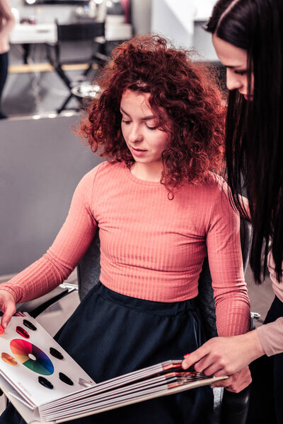 Nice pleasant red haired woman looking at the catalogue