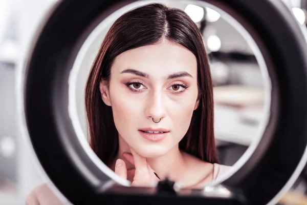 Serios femeie drăguță uita-te la fața ei în oglindă — Fotografie, imagine de stoc