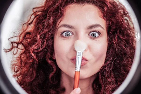 Encantada mulher agradável brincando com uma escova de maquiagem — Fotografia de Stock