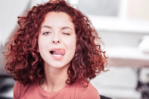 Happy playful woman showing her tongue to you