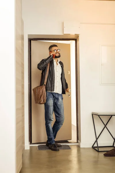 Handsome tall short-haired bearded man with a bag speaking on the phone — Stock Photo, Image