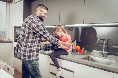 Pembe bir t-shirt sevimli uzun saçlı kız eğleniyor babasıyla birlikte mutfakta