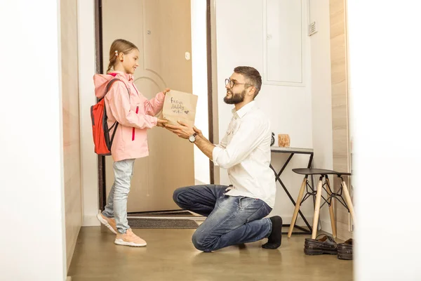 Grand homme barbu aux cheveux bruns dans des lunettes de vue donnant un cadeau à une jolie fille — Photo