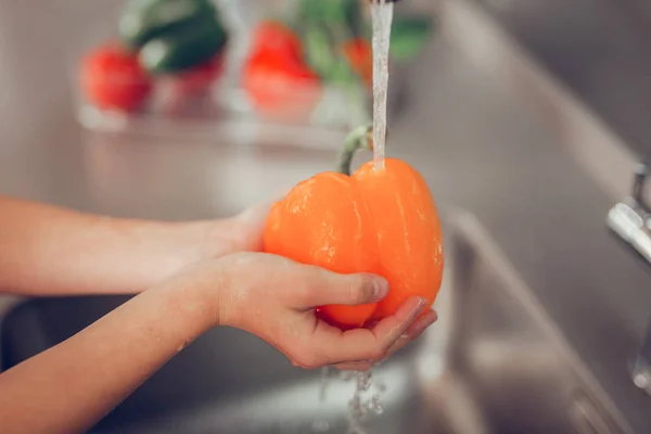 Malá holčička mytí zářivě oranžové zeleniny v podložka — Stock fotografie