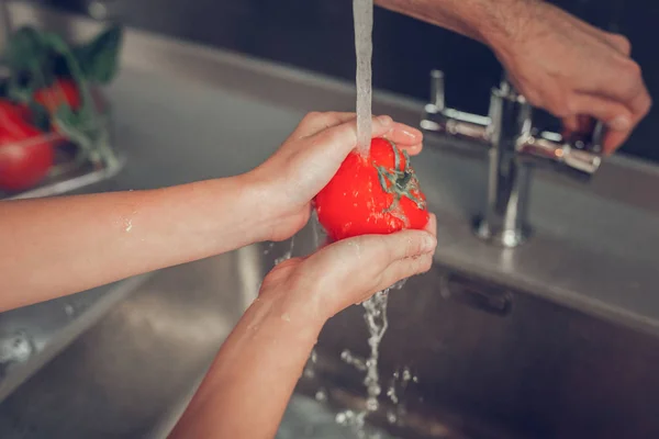 Kleines Mädchen wäscht vor dem Frühstück eine Tomate in der Waschmaschine — Stockfoto