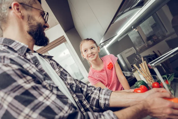 Carino ragazza dai capelli lunghi in una t-shirt rosa guardando attentamente a suo padre — Foto Stock