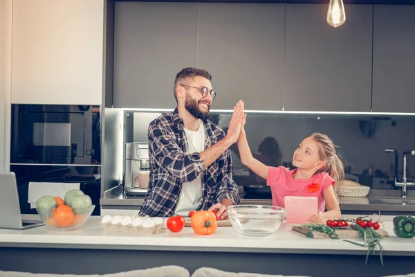 Tall bebaarde dark-haired mens in een geruit overhemd maken van ontbijt met zijn dochter — Stockfoto