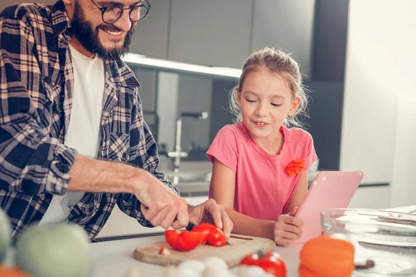 Knappe dark-haired bebaarde man in een geruit overhemd snijden tomaten — Stockfoto