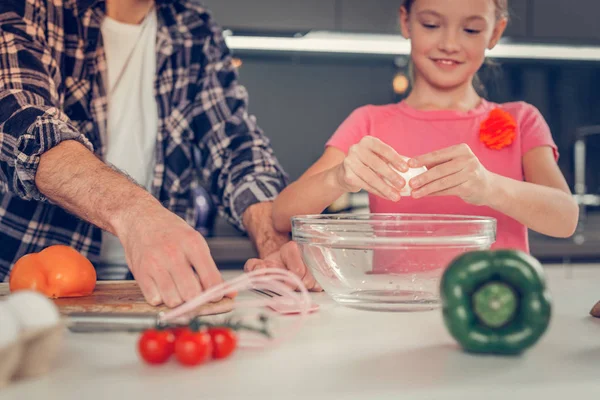 Mooie blonde meisje in een roze t-shirt een ei breken — Stockfoto