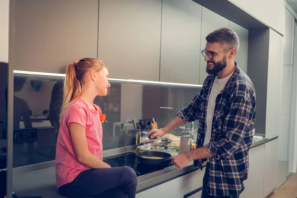 Lachende schattig meisje in een roze t-shirt kijken naar haar vader — Stockfoto