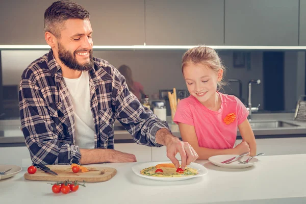 Bearded tall man in a checkered shirt putting cherry tomato on the omelet — Stock Photo, Image