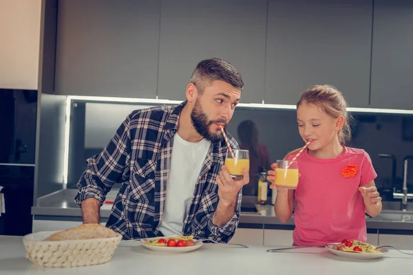 Barbudo homem alto em uma camisa quadriculada e sua filha bonita desfrutando de café da manhã — Fotografia de Stock
