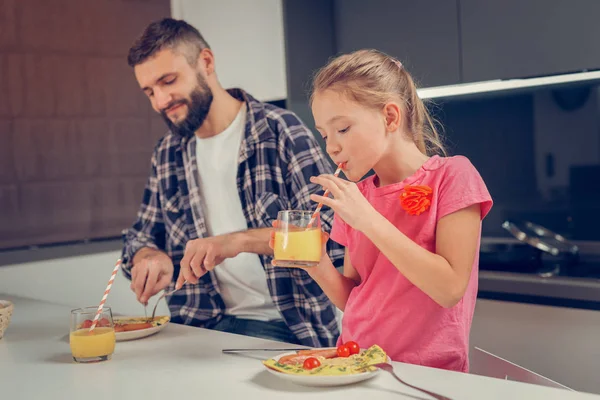 Barbuto uomo alto in una camicia a scacchi e la sua graziosa figlia mangiare frittata — Foto Stock