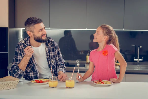 Carino ragazza dai capelli biondi in una t-shirt rosa e suo padre sorridendo l'un l'altro — Foto Stock