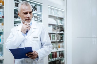 Gri saçlı sakallı eczacı ilaç karşılaştırma mavi gömlekli