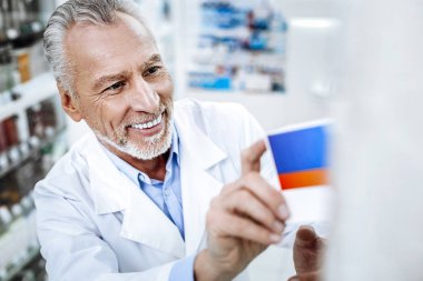 Kara gözlü güneş yanığı ve eczacı parlak gülümsüyor beyaz önlük