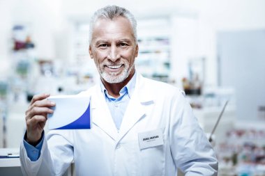 Kara gözlü sakallı beyefendi gülümseyerek mutlu bir şekilde beyaz önlük içinde