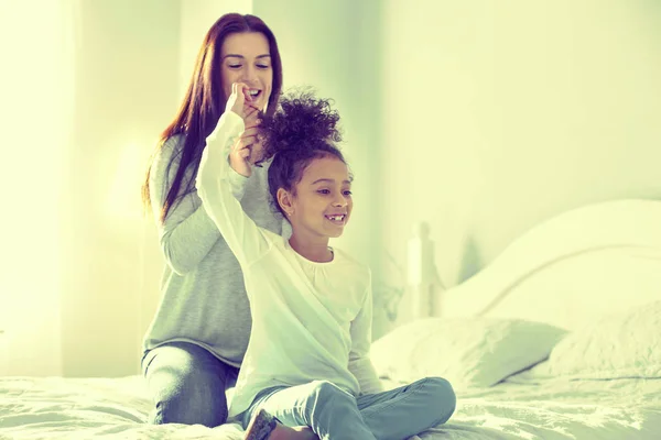 Ruhe sammelnde Mutter flechtet schöne Haare ihrer Tochter. — Stockfoto