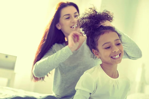 Cura responsabile mamma spazzolando i capelli della sua figlia mulatto . — Foto Stock