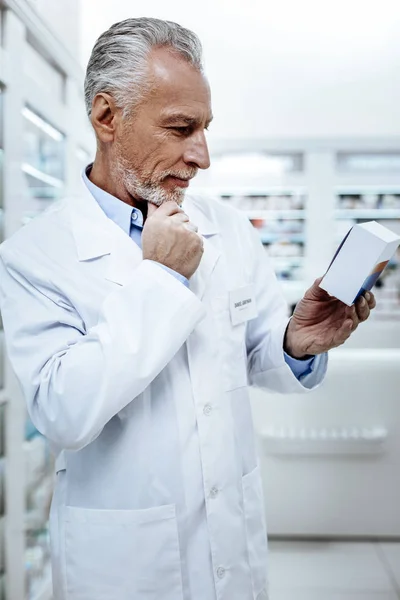 Бородатый симпатичный фармацевт с морщинами на лице, думающий о новом лекарстве — стоковое фото