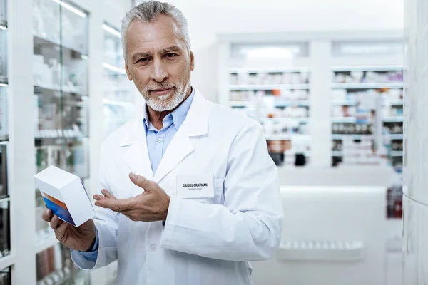 Bärtiger, gutaussehender Mann im weißen Mantel präsentiert ein neues Medikament — Stockfoto