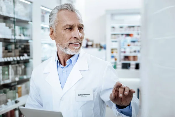 Director of a drugstore in a white coat examining the show case in a drugstore