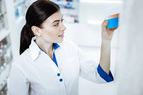 Bonita mujer de pelo largo con una bata blanca que toma el medicamento de una vitrina —  Fotos de Stock