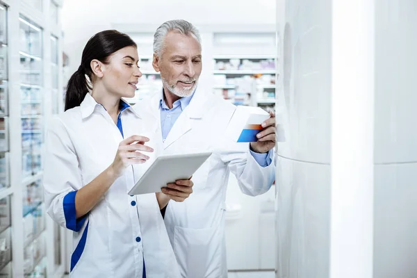 Director de una farmacia con una bata blanca y su asistente llenando el informe en línea — Foto de Stock