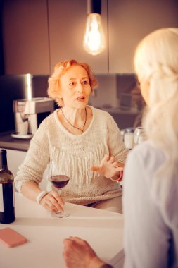 Bir kadeh şarap ile oturan güzel yaşlı kadın