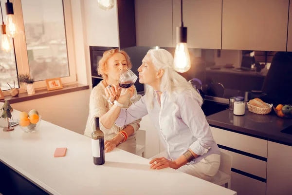 Щасливі старші жінки п'ють червоне вино разом — стокове фото