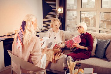 Nice smart aged women discussing different books clipart