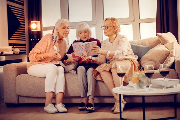 Encantadas mujeres agradables leyendo un libro juntas — Foto de Stock