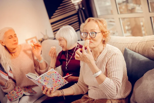 Mulher idosa positiva agradável cheirando um biscoito — Fotografia de Stock