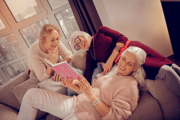 Vrolijke aangename vrouw liggend met een boek in haar handen — Stockfoto