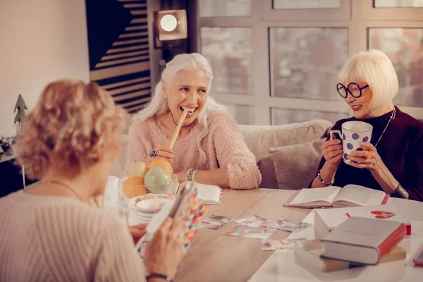 Happy aged woman trying a tasty cookie — Stock Photo, Image