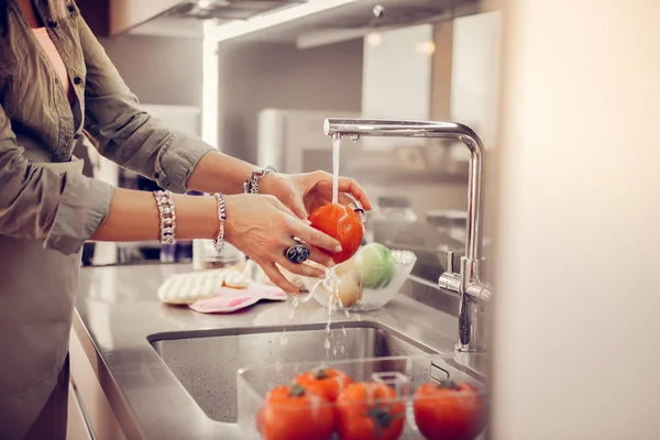 Aangename senior vrouw wassen tomaten in de gootsteen — Stockfoto