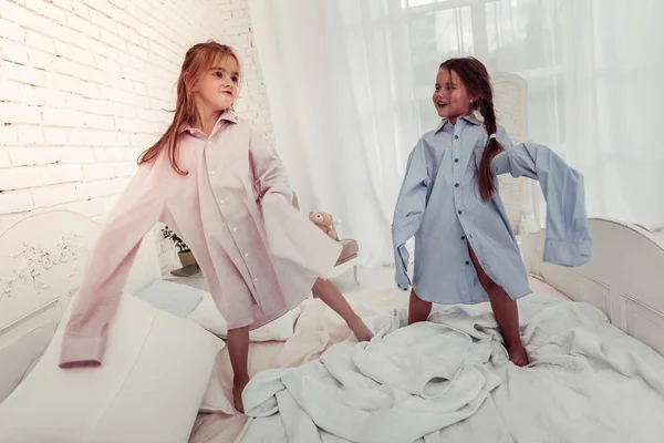 Радостные счастливые девушки, играющие вместе на кровати — стоковое фото
