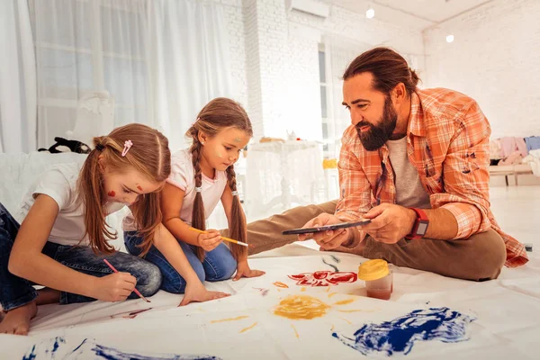 Bel homme barbu aidant ses filles à peindre — Photo