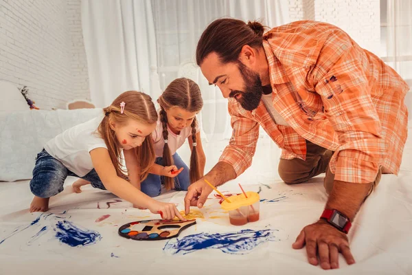 Schöner bärtiger Mann, der Mädchen beibringt, auf Stoff zu malen — Stockfoto