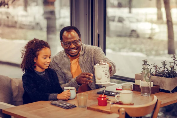 Curly filha vestindo suéter tomando café da manhã com o pai — Fotografia de Stock