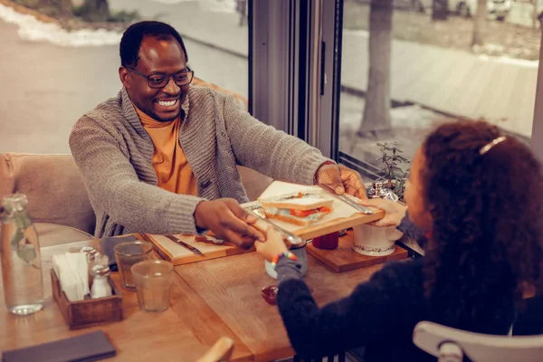 Отец дает деревянную тарелку с бутербродом своей милой дочери — стоковое фото
