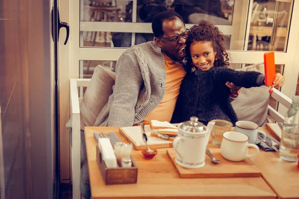 Filha bonito segurando seu smartphone fazendo foto com o pai — Fotografia de Stock