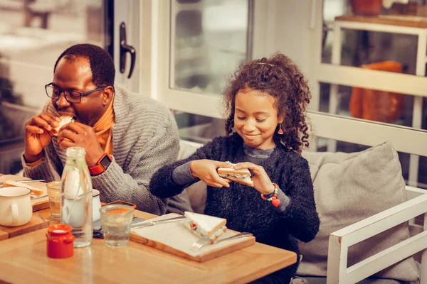 Father and daughter feeling satisfied while eating tasty sandwiches — Stock Photo, Image